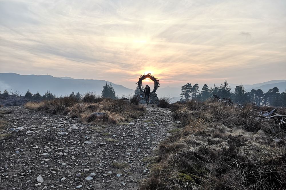 Cyclist passing The Viewpoint sculpture on the Great Glen Way high route