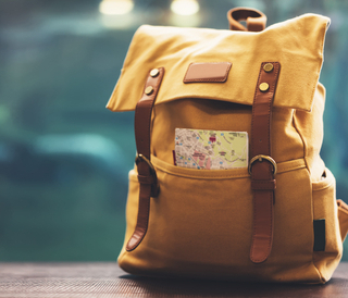 A backpack sitting on a table with a map in the front pocket