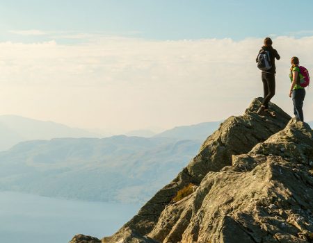 two woman atop a hill hiking safely up a mountain in the Scottish Highlands
