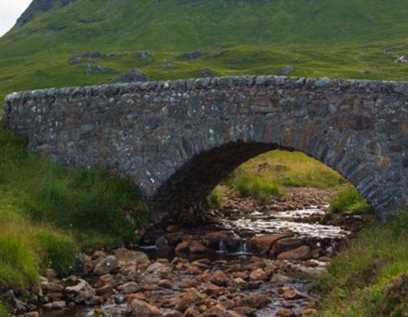 A small tent by an old stone bridge in the Scottish Highlands