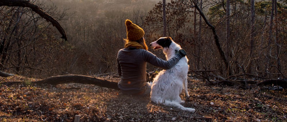 Lady sitting in a forest with her dog