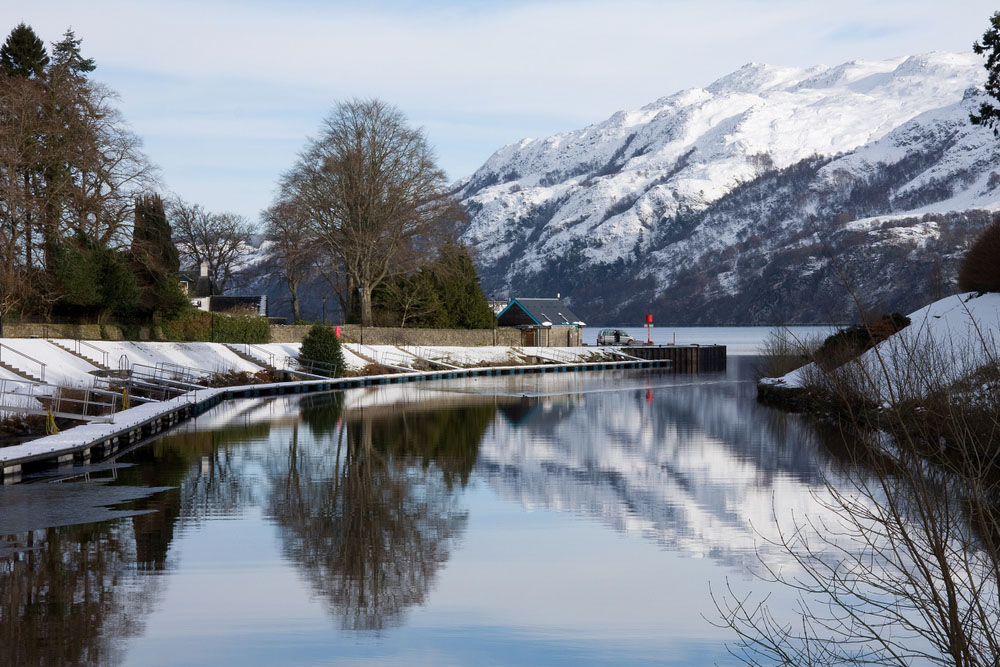 The Caledonian Canal going into Loch Ness on a snowy winters day with snowy mountains in the background