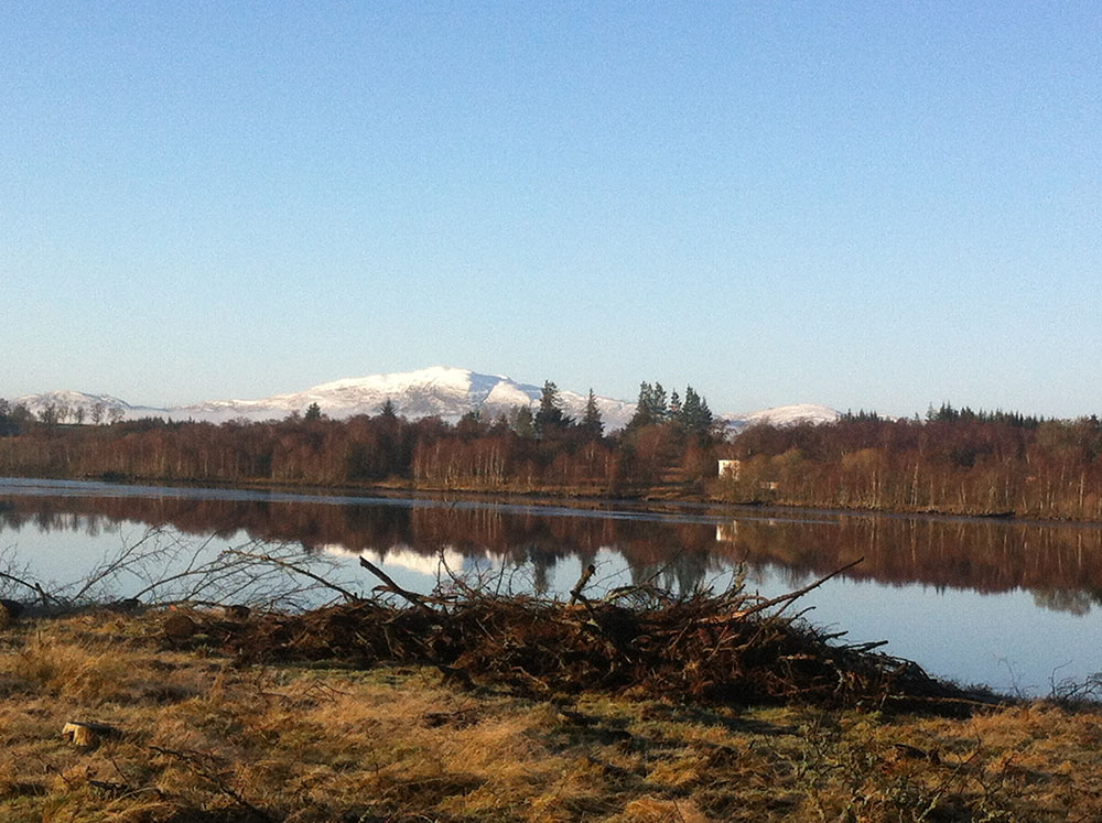 A loch on the Loch Ness 360 trail with snow capped mountains in the background