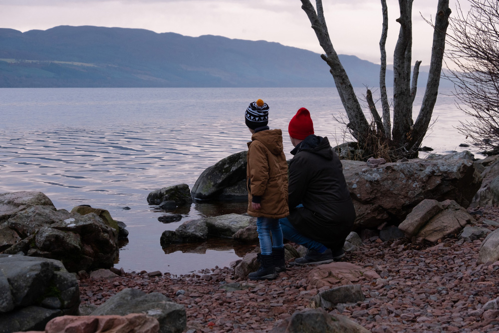 People in warm winters clothes on the banks of a loch in Scotland
